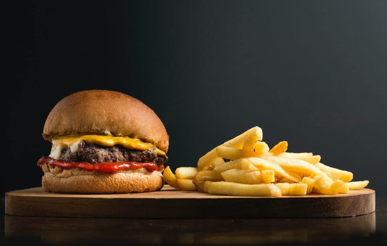 A cheeseburger and fries against a black background.